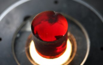 Frisch aus der Schmelze erstarrte Zinkoxid-Kristalle schimmern rot, weil sie noch atomare Defekte enthalten. Ein nachfolgendes Tempern – Erhitzen auf ca. 1000°C – bringt die Defekte zum Verschwinden und liefert ein blassgelbes Material, das zu Halbleiter-Wafern verarbeitet wird (Foto: IKZ)